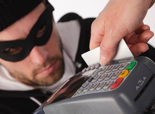 Um homem com uma venda nos olhos, dando a entender que é um ladrão e vai roubar os dados de um cartão. Fraudes no cartão de crédito.
