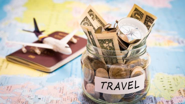 Um pote com moedas e dinheiro, um passaporte e um avião de brinquedo em cima de um mapa, para viajar sem dívidas.