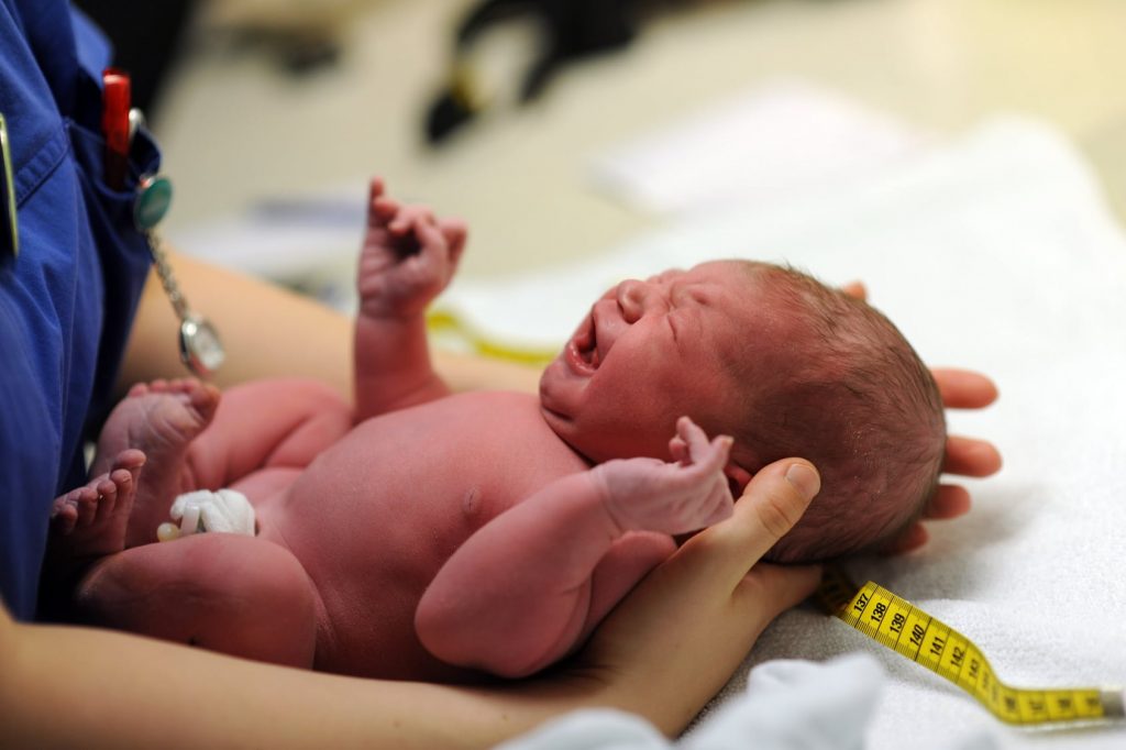 Um bebê recém nascido sendo avaliado por uma pediatra. Como se programar financeiramente para ter o primeiro filho.